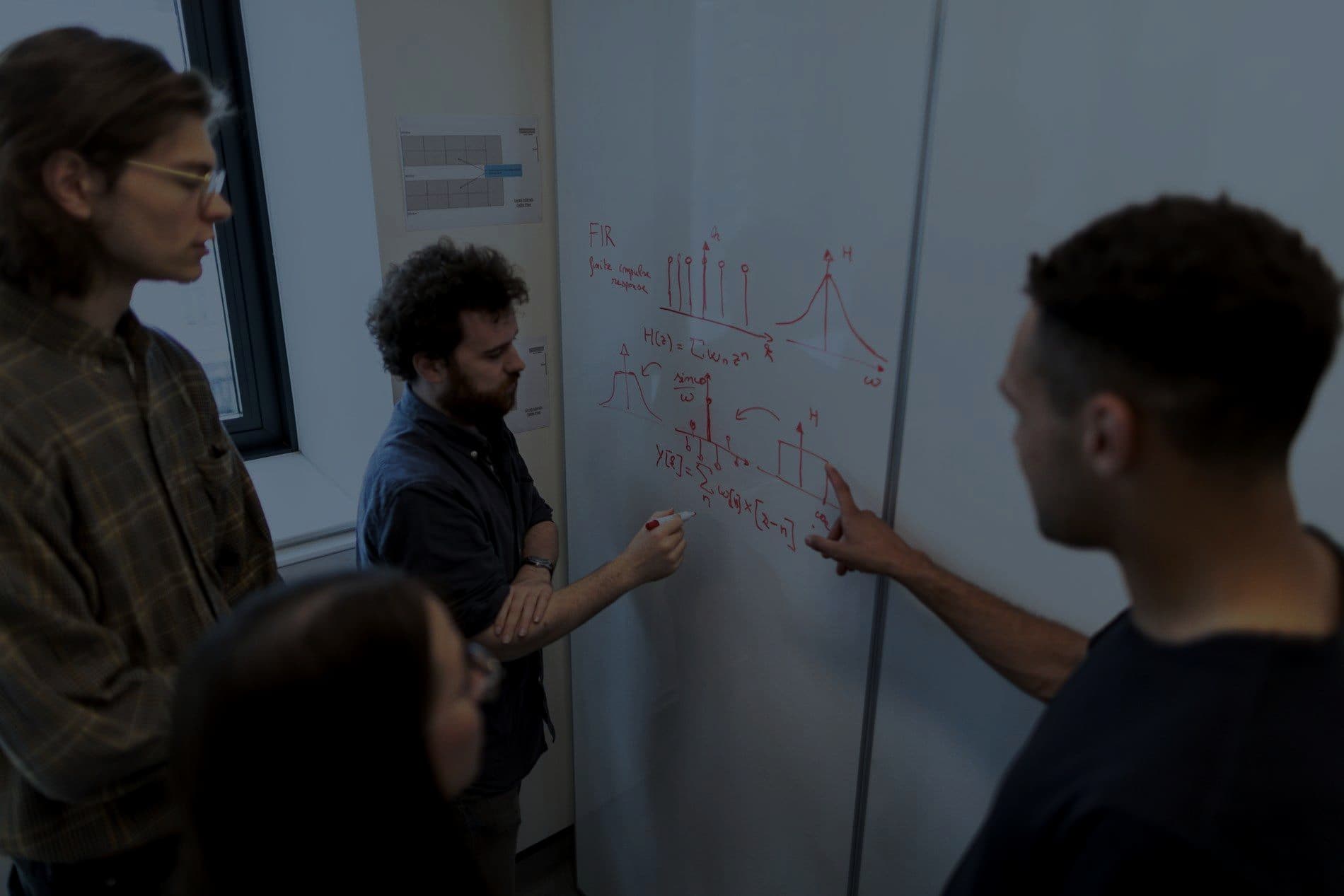 Engineers sketching a system diagram together on a whiteboard
