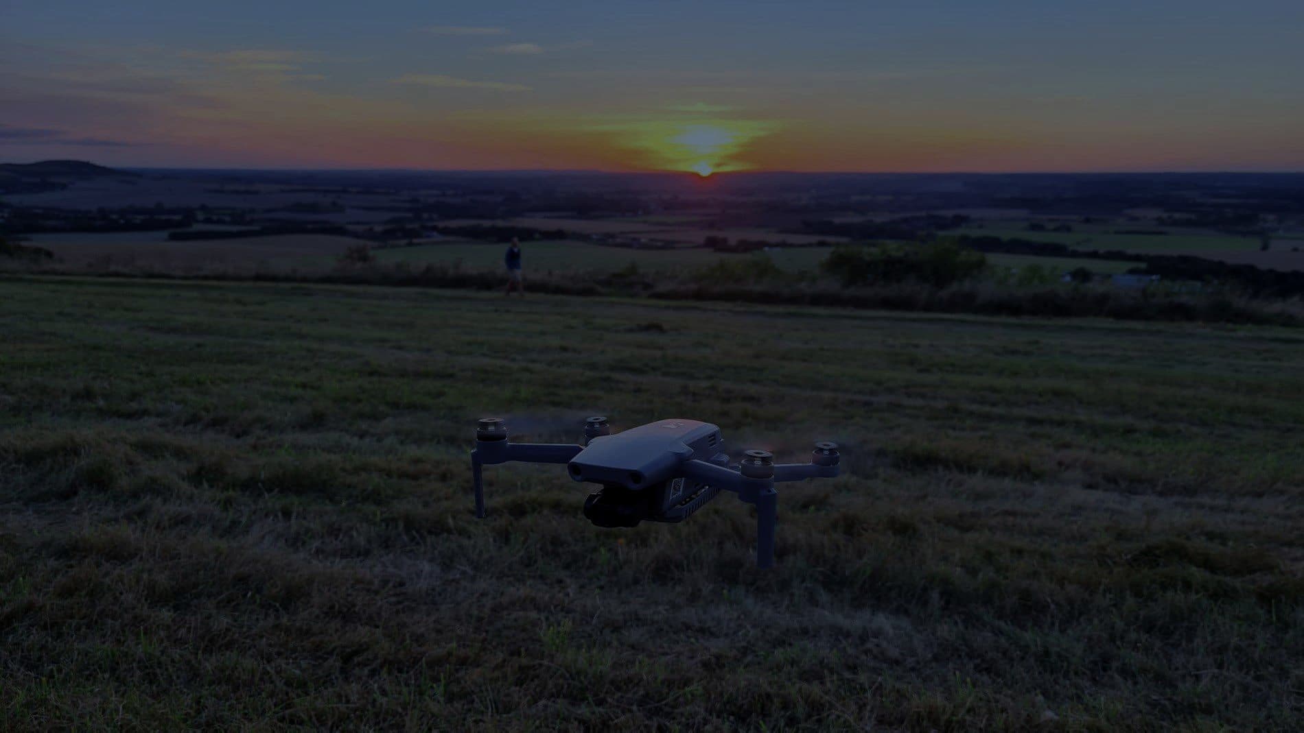 A survey drone flying low over farmland at sunset