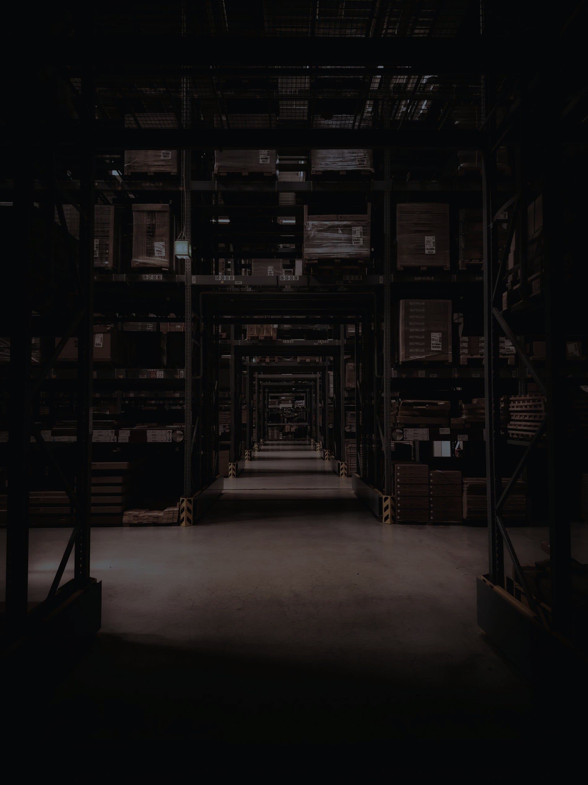 Aisles of storage racking in a dark warehouse