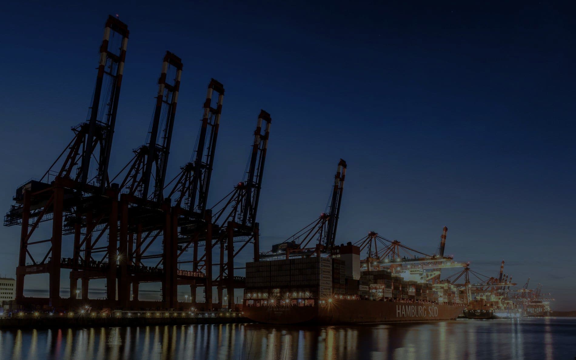 Container cranes along a port quayside at dusk