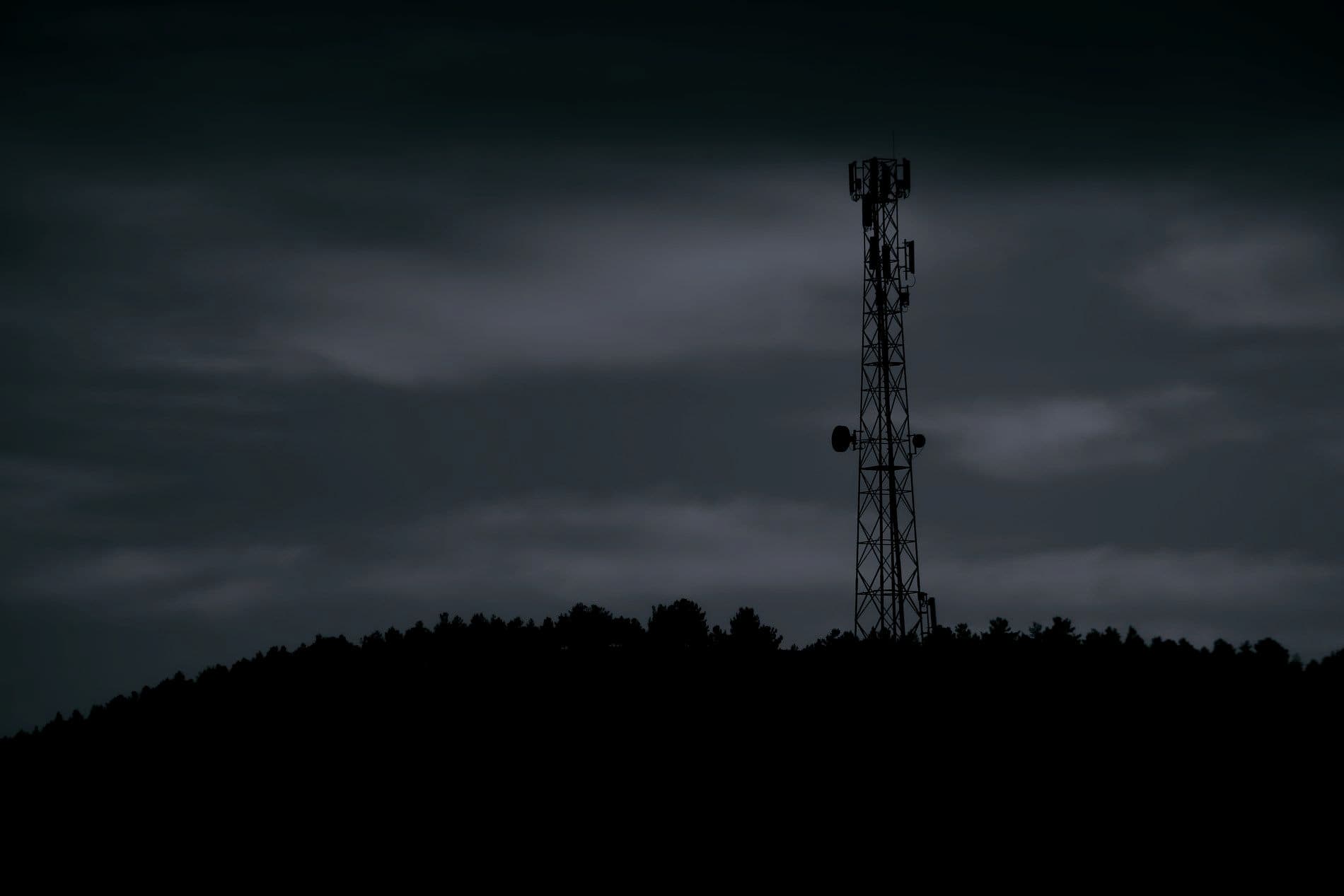 A telecommunications tower silhouetted against a night sky